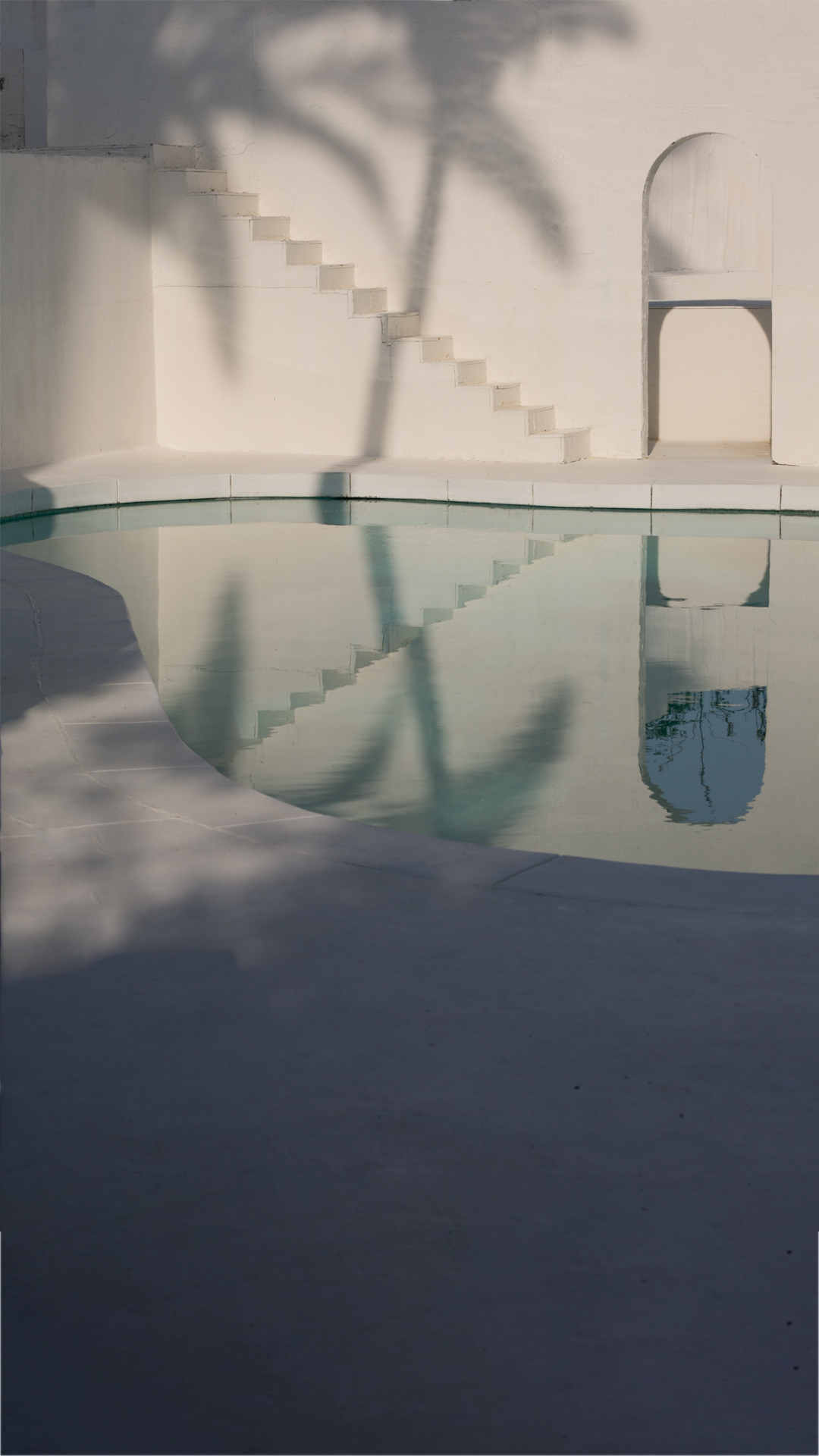 Golden hour by the curved white-plaster pool at Caster House, a Santorini-style shoot location in Los Angeles